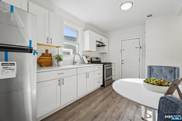 a kitchen with stainless steel appliances granite countertop a sink a stove a dining table and chairs