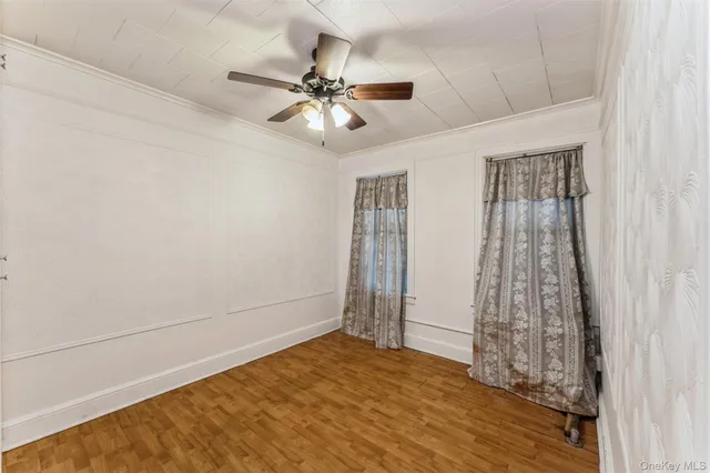 a view of an empty room with window and chandelier fan