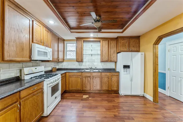 a kitchen with stainless steel appliances granite countertop a refrigerator a sink dishwasher a stove and white countertops with wooden floor