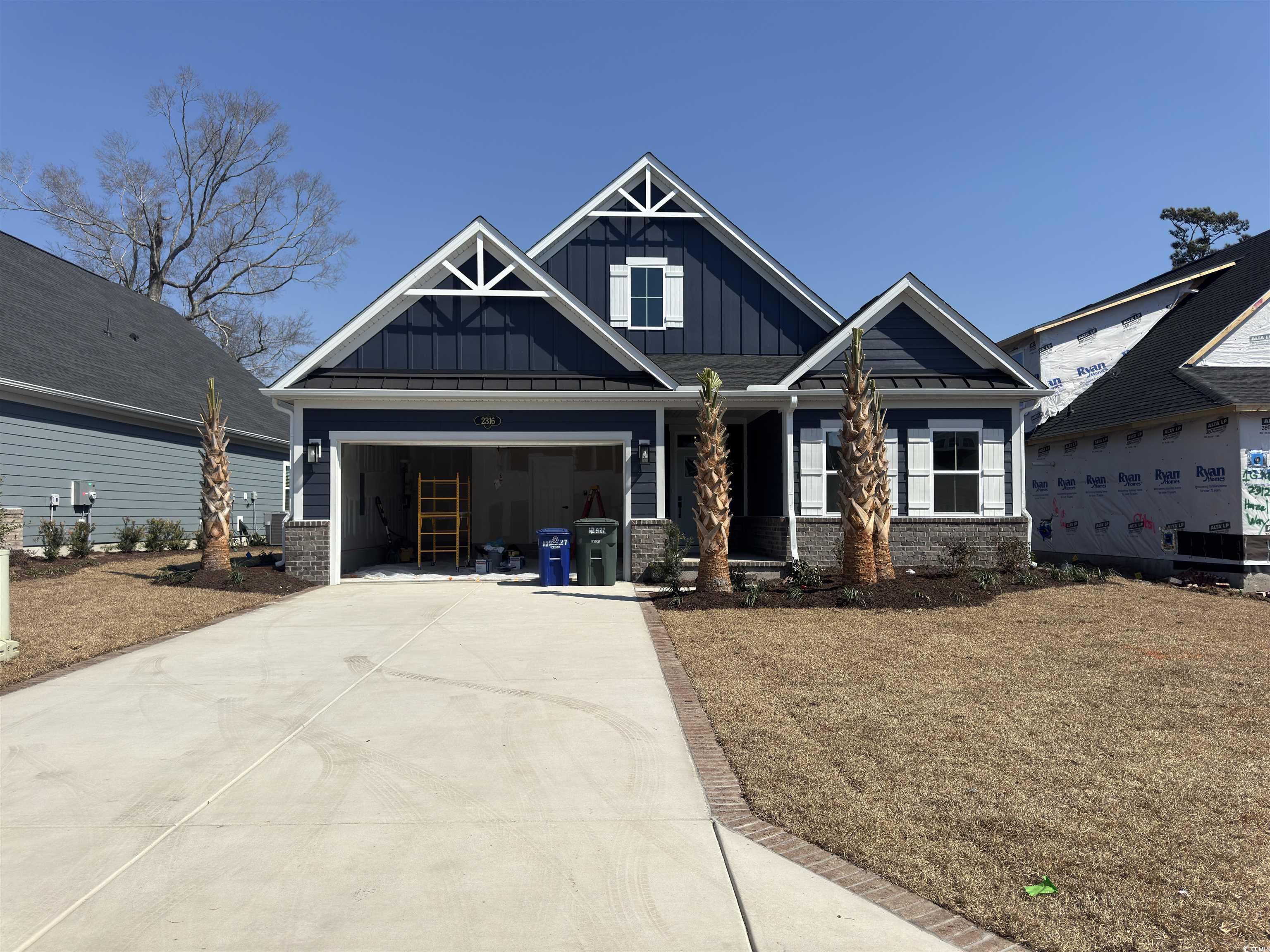 Craftsman-style home featuring driveway, brick sid