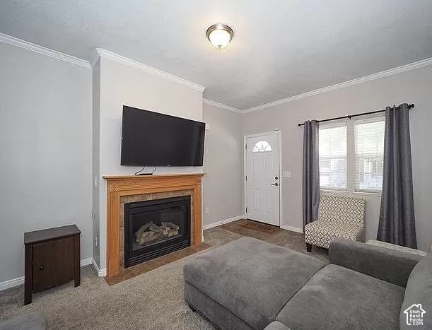 13548 South Villa Rosa Way Draper, UT 84020 - Photo 3 of 28 Living area featuring a gas fireplace with a wood-finish mantel and stone surround, crown molding, and neutral-toned carpeting