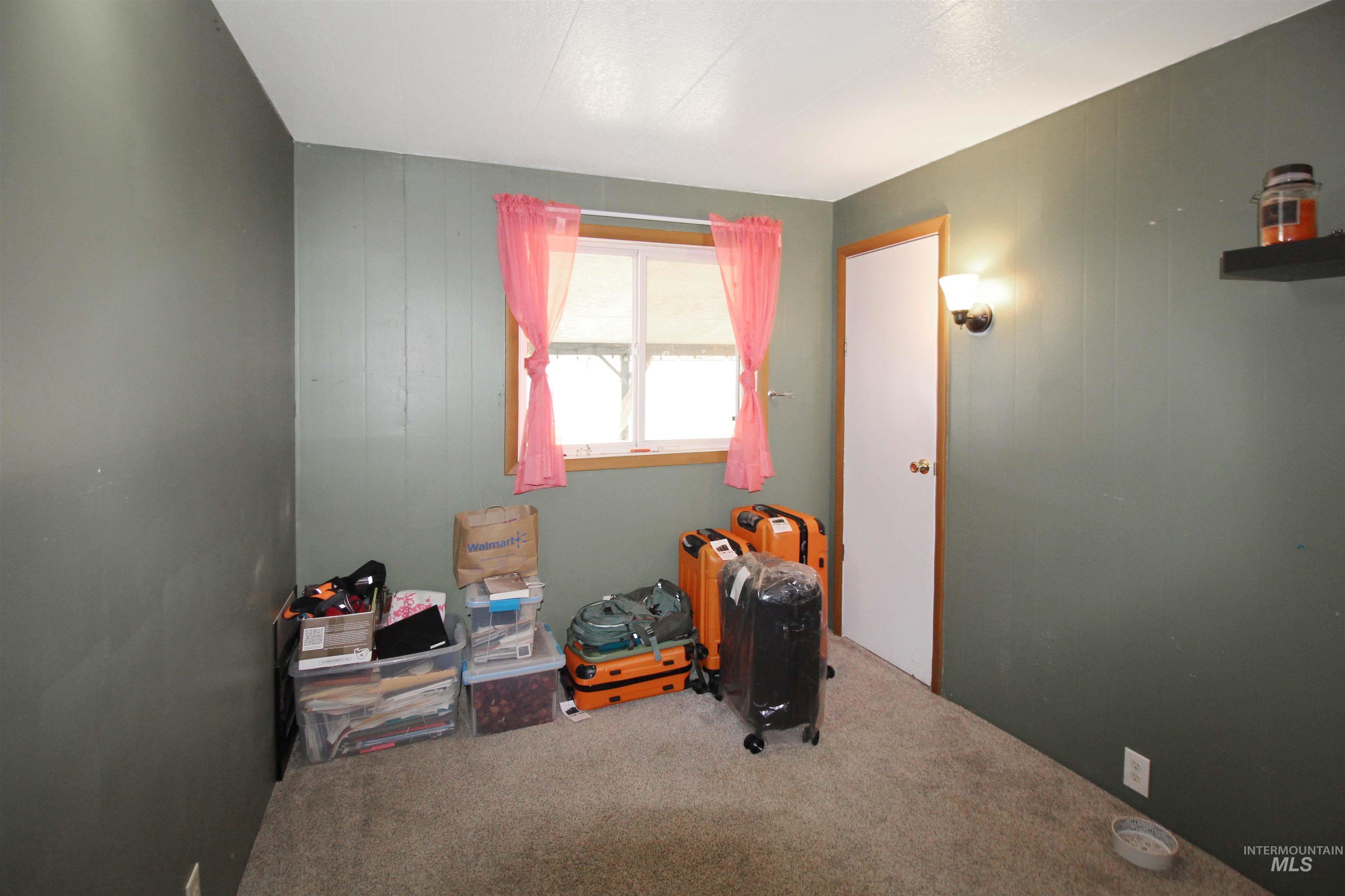 1265 Pioneer Road Weiser, ID 83672 - Photo 21 of 29 Room featuring neutral-toned carpet flooring, a window with wood trim, a built-in wall sconce, and a white door with wood trim