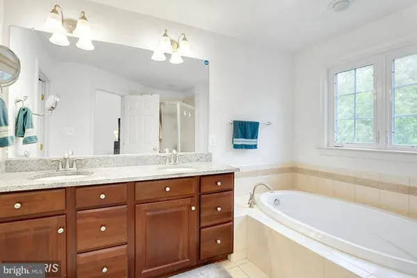 a bathroom with a granite countertop bathtub a sink double vanity and window