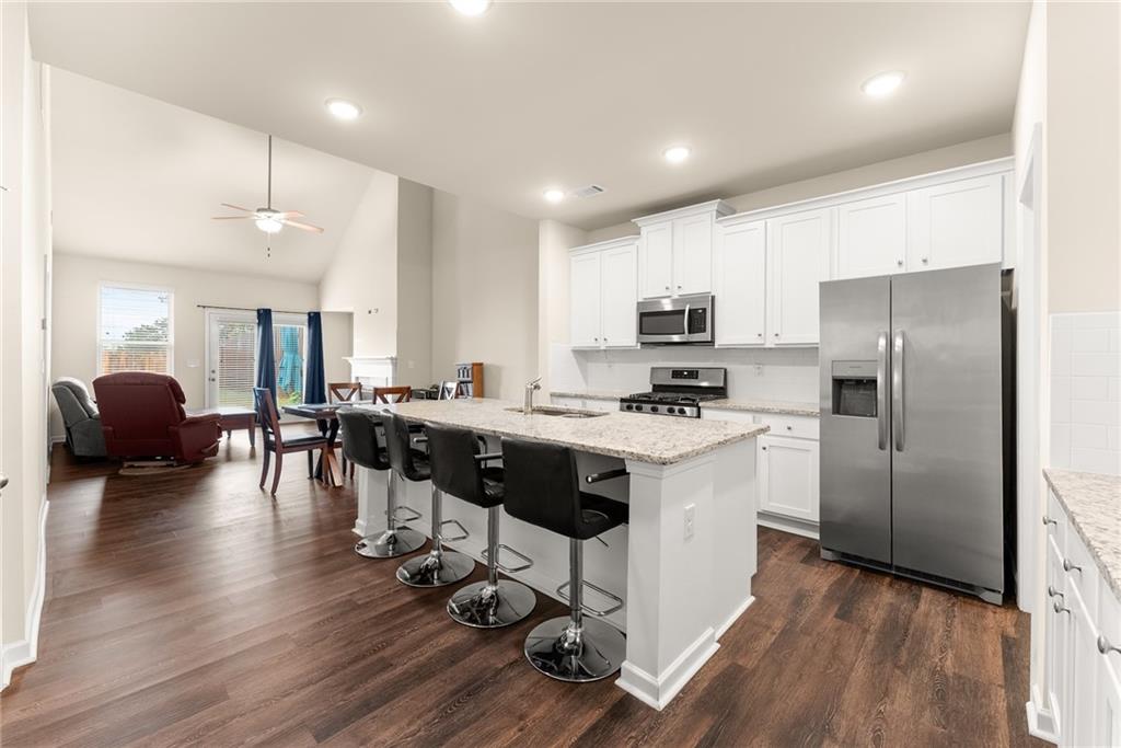 3914 Prospect Point Drive Oakwood, GA 30566 - Photo 5 of 30 a kitchen with granite countertop a refrigerator a stove a sink a dining table and chairs with wooden floor