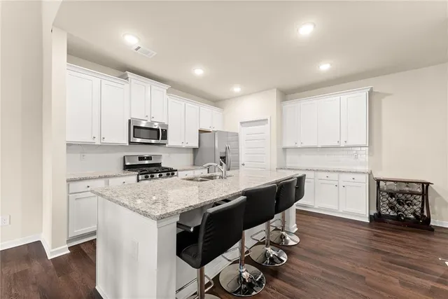 a kitchen with a sink a stove a refrigerator cabinets and wooden floor
