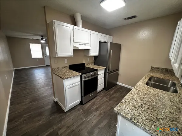 a kitchen with granite countertop a stove and a refrigerator
