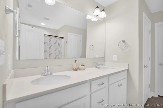 a bathroom with double vanity sinks a vanity a lamp and a mirror