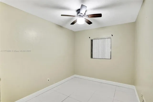 an empty room with a window and a fan