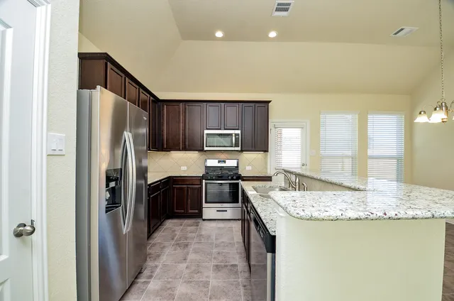 a kitchen with stainless steel appliances granite countertop wooden cabinets and a granite counter tops