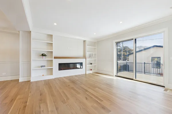a large kitchen with stainless steel appliances kitchen island a large counter top a stove a chimney a sink and a living room view