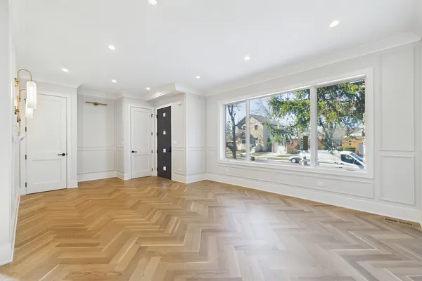 an empty room with wooden floor chandelier and windows