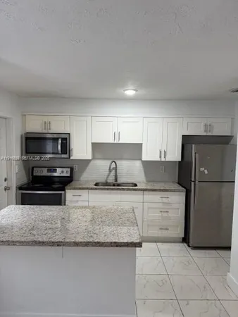 a kitchen with granite countertop a refrigerator and a stove top oven