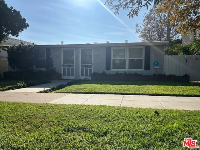 a view of a house with a yard and a large tree