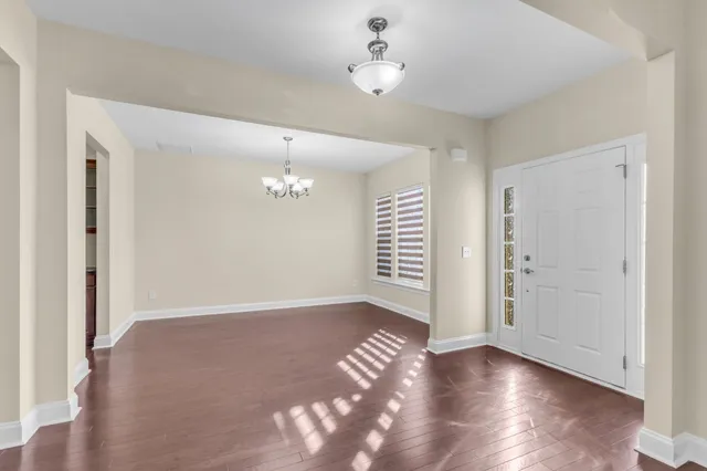 an empty room with wooden floor chandelier fan and closet area