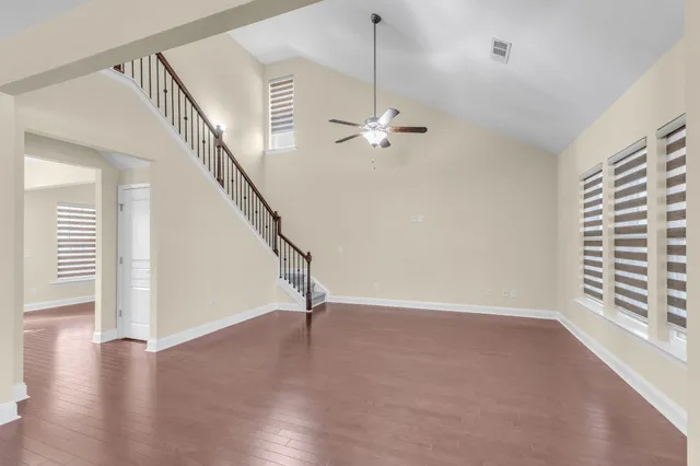 a view of an empty room with a window and wooden floor