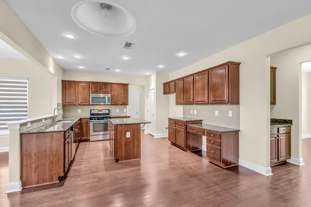 a large kitchen with stainless steel appliances granite countertop lots of counter top space and wooden floor
