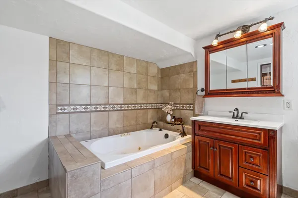 a bathroom with a tub sink and mirror