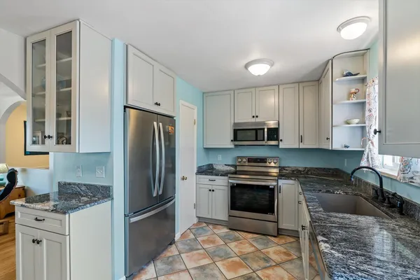 a kitchen with granite countertop a stove a refrigerator and a cabinets