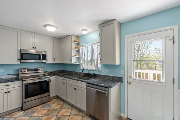 a kitchen with stainless steel appliances granite countertop a stove a sink and a microwave