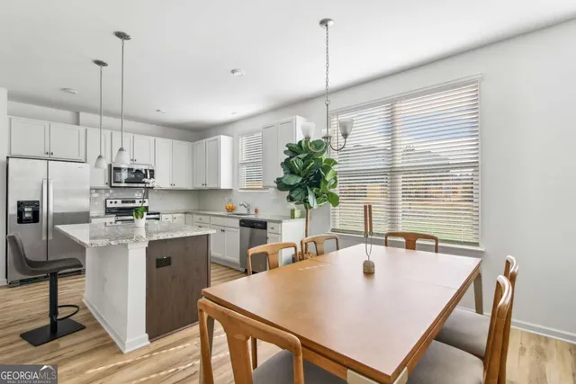 a large kitchen with a table chairs sink and refrigerator