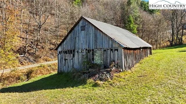 a view of a wooden house with a yard and wooden fence