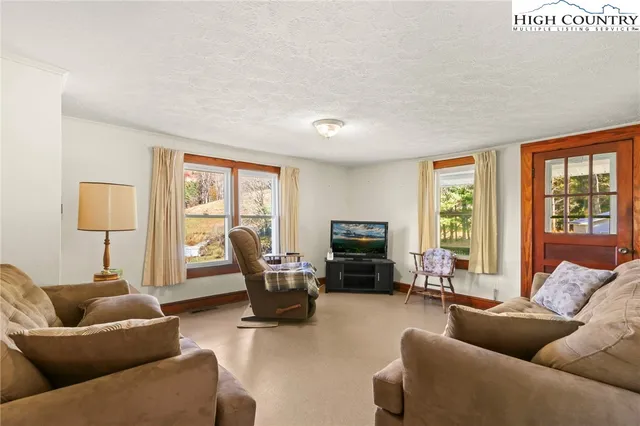 a living room with furniture floor to ceiling window and a flat screen tv
