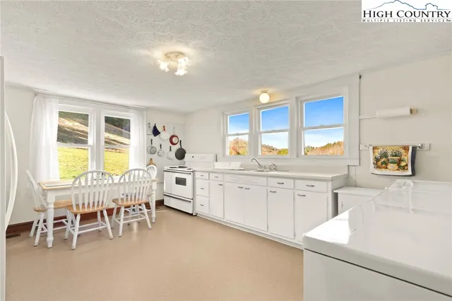 a large white kitchen with furniture a chandelier and a large window