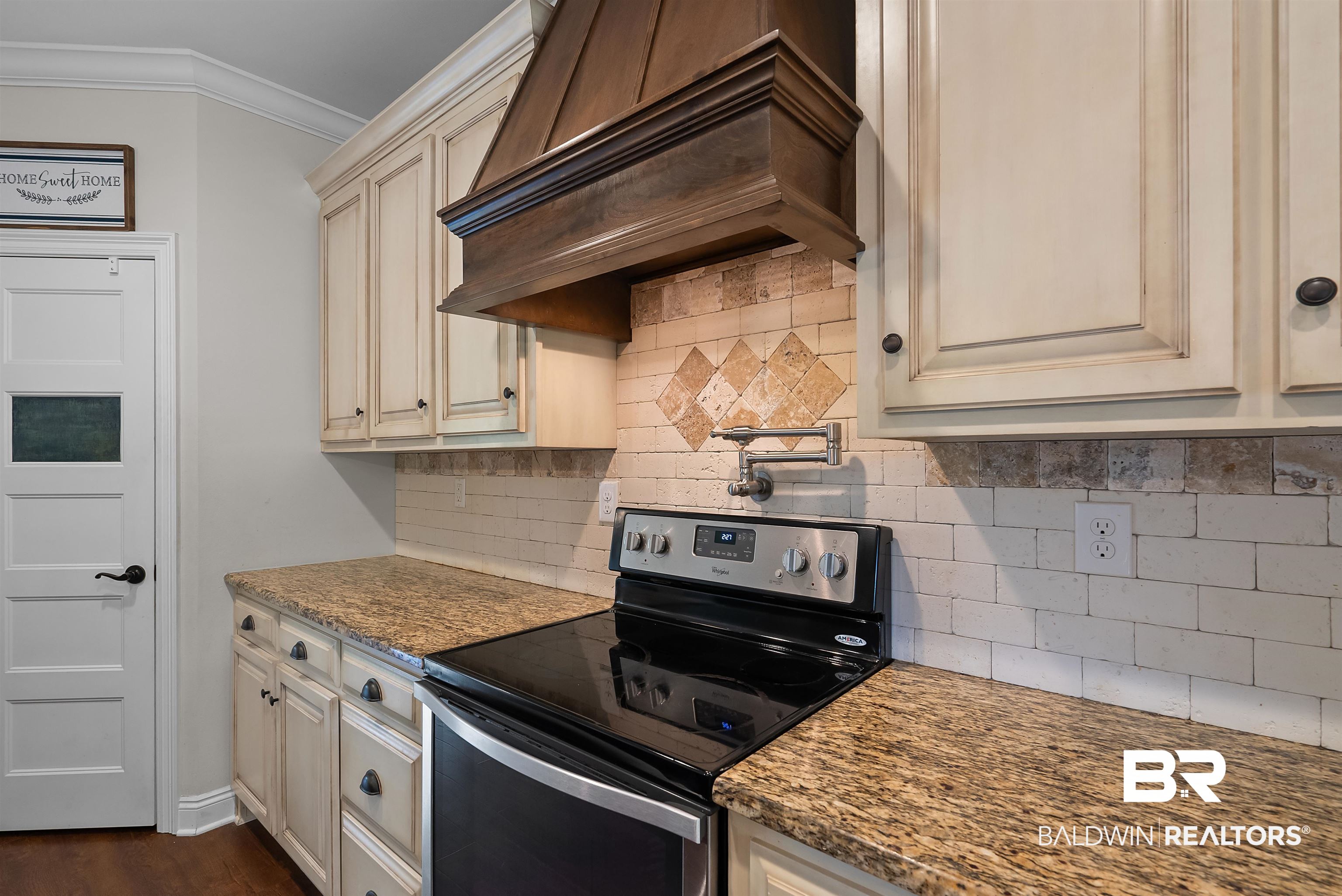 12070 Comalander Road Fairhope, AL 36532 - Photo 15 of 50 Kitchen featuring a stainless steel range with a pot filler, a custom wood range hood, light-toned cabinetry, granite countertops, and a subway tile backsplash