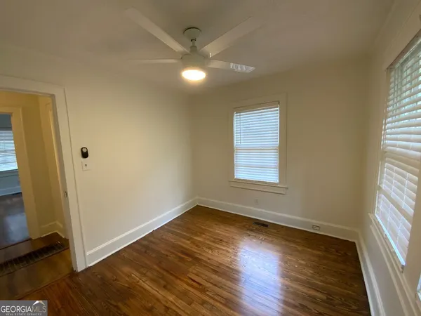 an empty room with wooden floor and windows