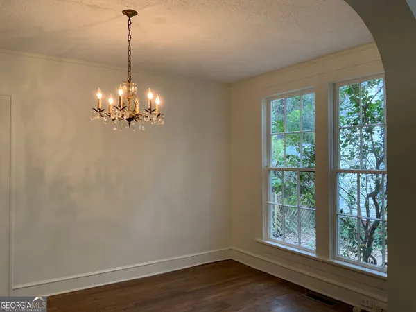 a view of a room with wooden floor chandelier and windows