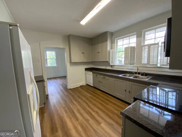 a large kitchen with granite countertop a large window a sink and stainless steel appliances