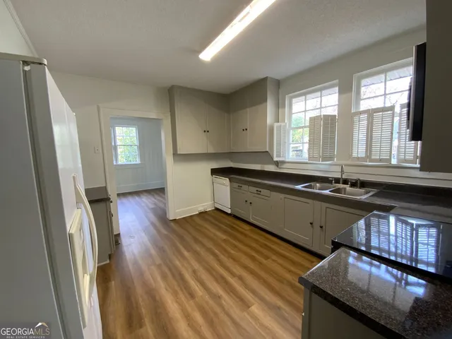 a large kitchen with granite countertop a large window a sink and stainless steel appliances