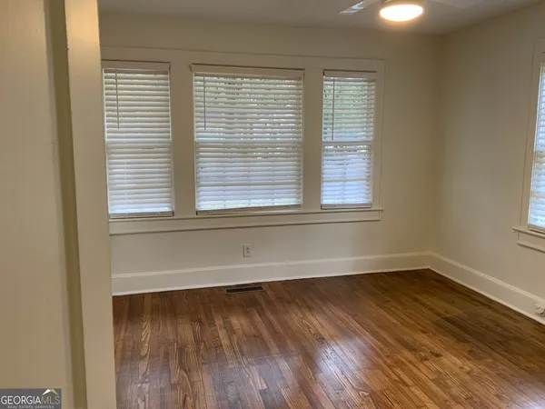 a view of an empty room with wooden floor and a window