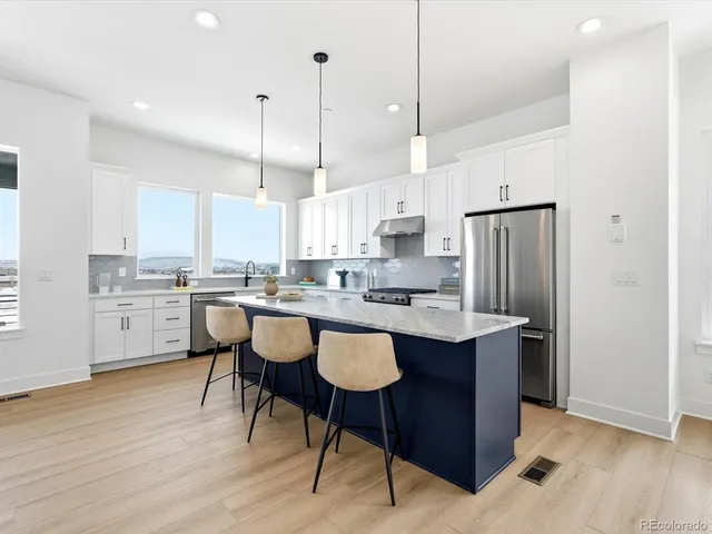 a kitchen with stainless steel appliances granite countertop a sink a stove a refrigerator and island with wooden floor