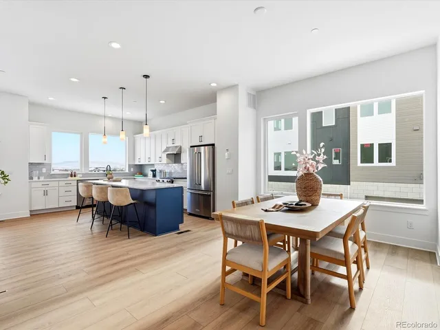 a kitchen with a dining table chairs and refrigerator