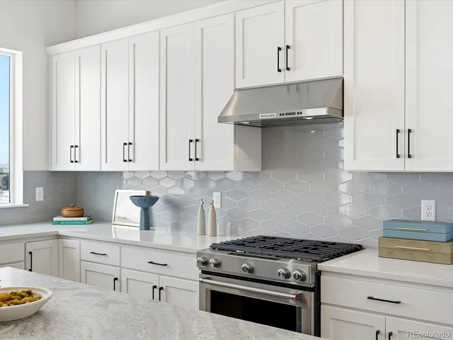 a kitchen with stainless steel appliances granite countertop white cabinets and a stove a oven with white countertops