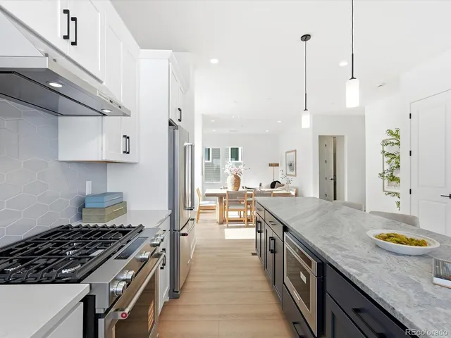 a kitchen with granite countertop a stove a chimney a sink and cabinets