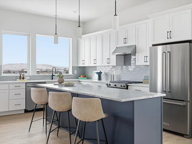 a kitchen with stainless steel appliances granite countertop a sink a stove a refrigerator and island with wooden floor