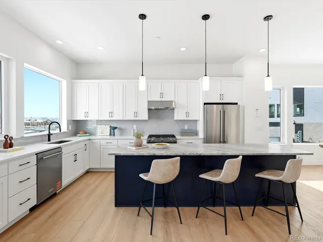 a kitchen with stainless steel appliances granite countertop a sink a stove a refrigerator and white cabinets