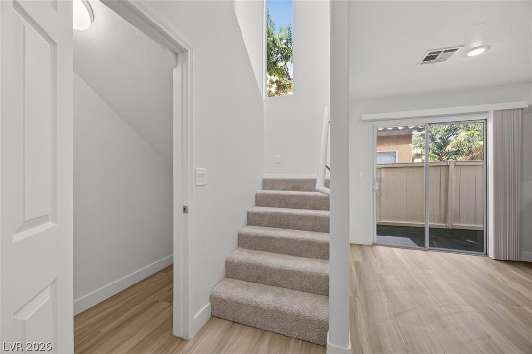 552 Albacate Street Henderson, NV 89015 - Photo 18 of 40 A split-level interior with warm wood flooring and a carpeted stairway leading to upper quarters, bathed in natural light.
