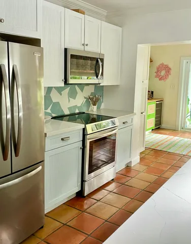 a kitchen with granite countertop a stove top oven microwave and refrigerator