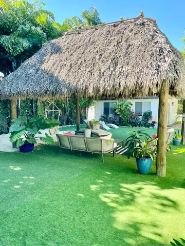 a view of a backyard with table and chairs potted plants and a large tree