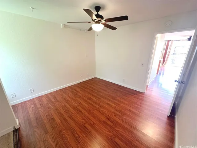a view of empty room with wooden floor and fan