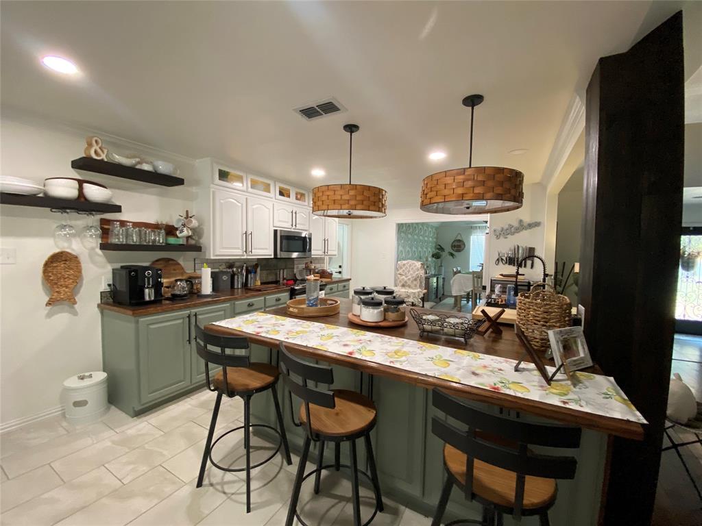 a kitchen with stainless steel appliances granite countertop a sink a stove a refrigerator and chairs