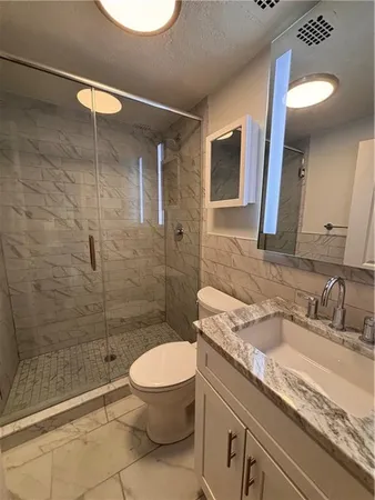 a bathroom with a granite countertop sink a toilet and shower