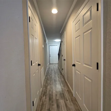 a view of a hallway with wooden floor and a bathroom