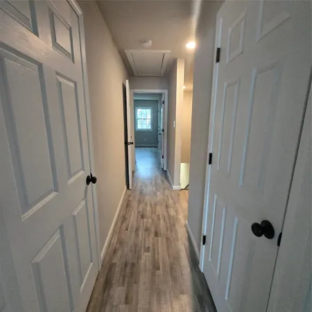 a view of a hallway with wooden floor and closet area