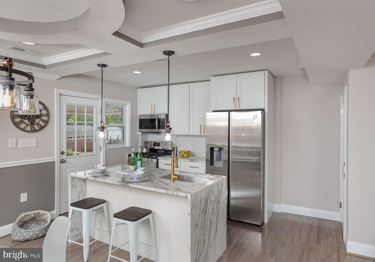 5923 Falkirk Road Baltimore, MD 21239 - Photo 12 of 27 a kitchen with stainless steel appliances granite countertop a refrigerator a sink a stove a dining table and chairs with wooden floor