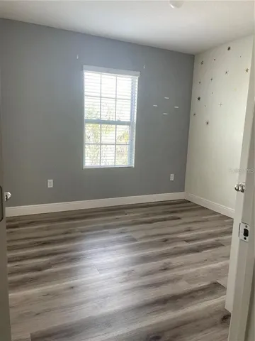 a view of empty room with window and wooden floor