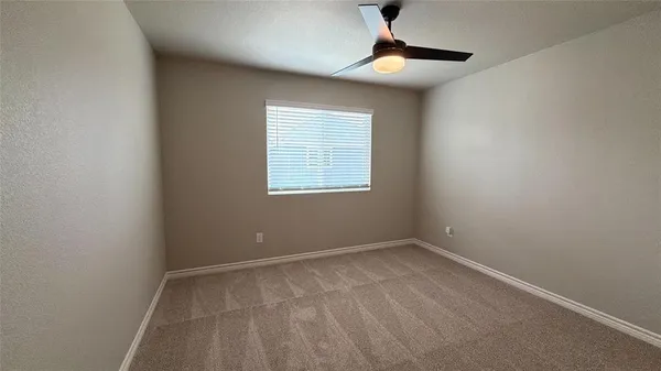 an empty room with a window and a fan